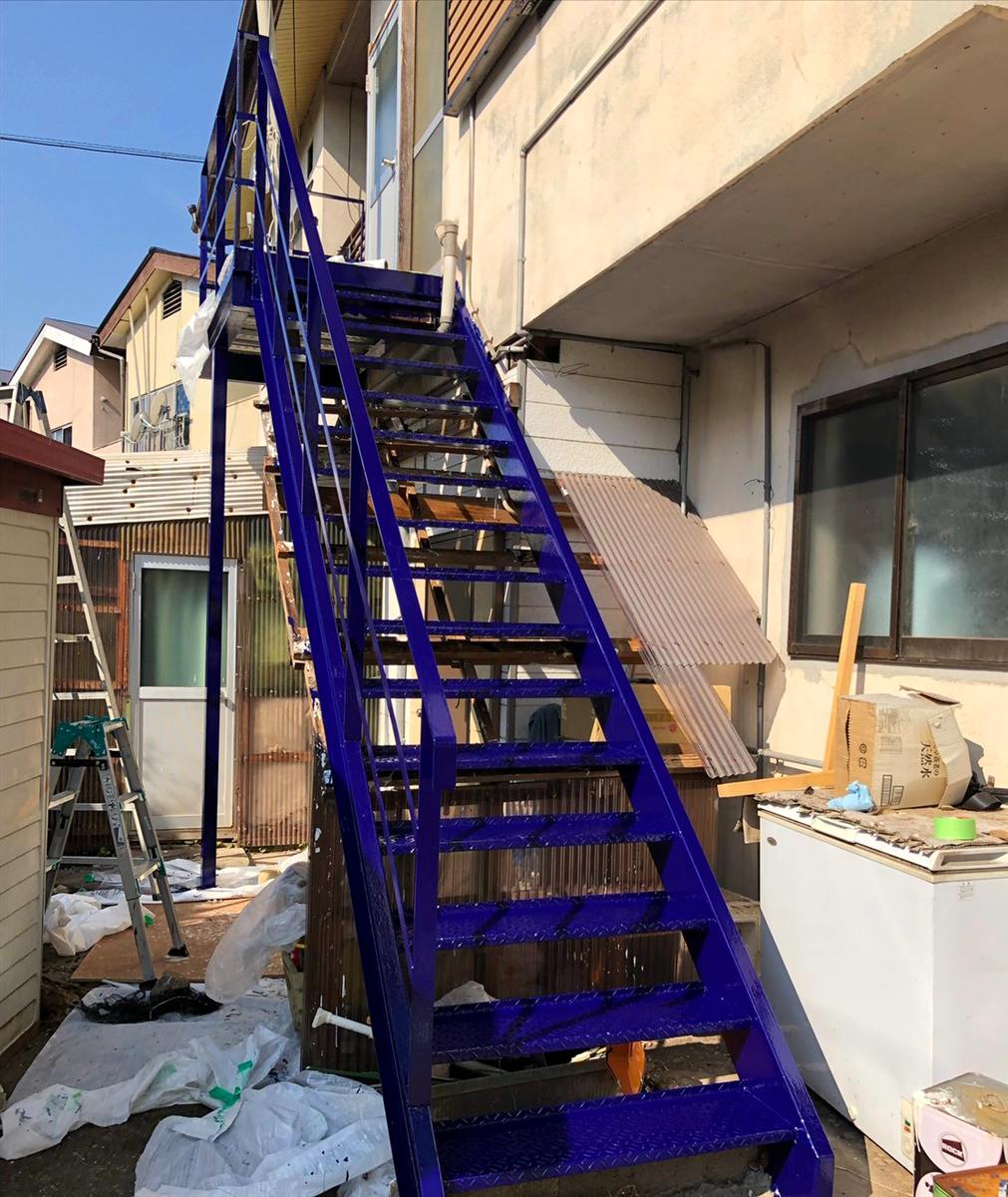 濃いブルーに塗装され仕上がった屋外階段の施工後の様子